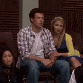 a man in a plaid shirt sits next to two women