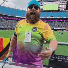 a man with a beard wears a tie dye shirt and sunglasses
