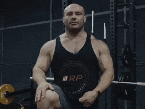 a bald man in a black tank top says " and then i fucking took one of my balls "