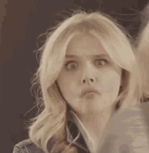 a woman with blonde hair is making a funny face with her mouth open .