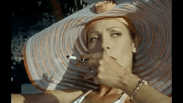 a woman wearing a hat is smoking a cigar .