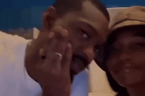 a man and a woman are posing for a picture and the man is wearing a wedding ring .