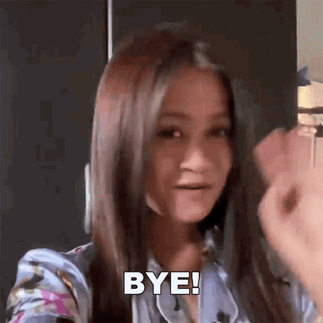 a woman is waving her hand and saying bye