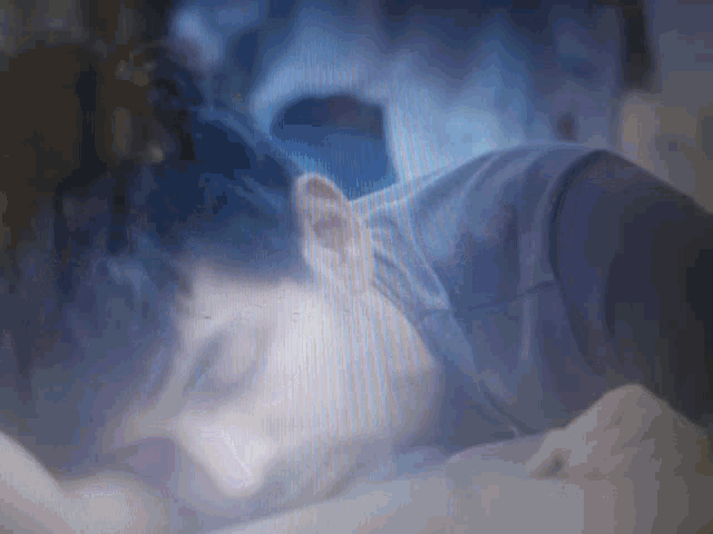 a blurry picture of a person laying on a bed with their eyes closed