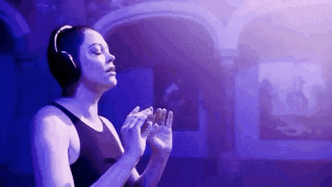a woman is wearing headphones and praying in a dark room .