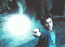 harry potter is holding a wand in his hand and pointing at a light .
