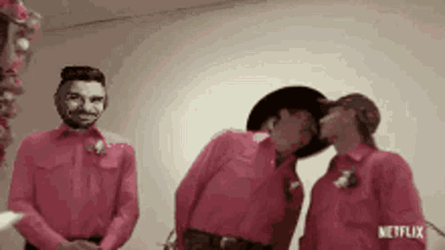 a man in a cowboy hat kisses a woman in a pink shirt