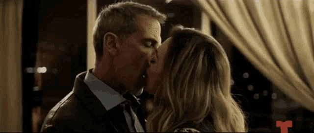 a man in a suit and tie is kissing a woman in a restaurant .