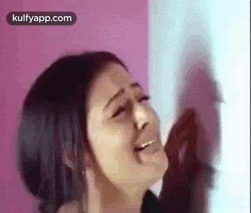 a woman is crying and looking at herself in the mirror .
