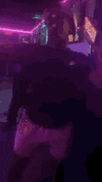 a man is dancing in a room with purple lights .