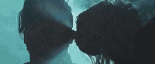a man and a woman are kissing in a dark room with smoke coming out of their mouths .