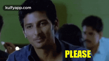 a man is sitting at a table with a group of people and a sign that says `` please '' .