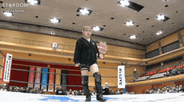 a woman stands in a wrestling ring with a sign that says stardom in the background