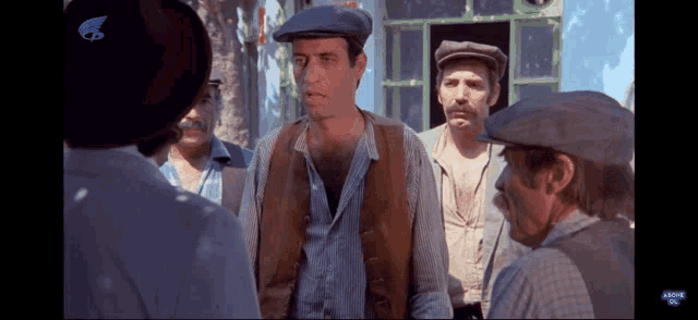 a group of men are standing in front of a building talking to each other