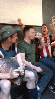 a man wearing a shirt that says ' slazenger ' on it drinks from a glass