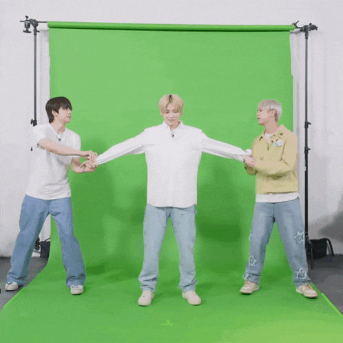 three men are standing in front of a green screen