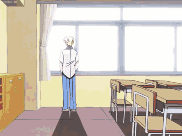 a man standing in a classroom looking out a window