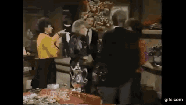a group of people are standing around a table with food .