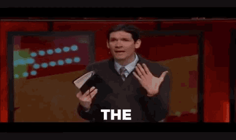 a man in a suit and tie is holding a bible and making a funny face .