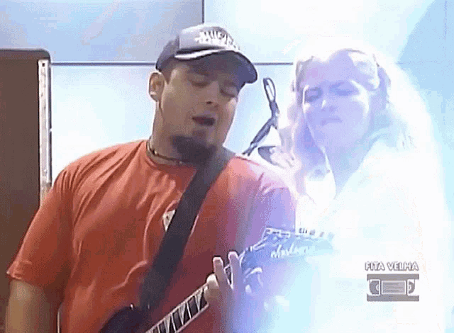 a man in a red shirt is playing a guitar while a woman looks on behind him with the words rua velha below him