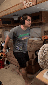a man wearing headphones and a shirt that says colorado is dancing in front of a fan
