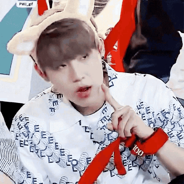 a young man wearing a headband with bunny ears is holding a red wristband with the number 100 on it .