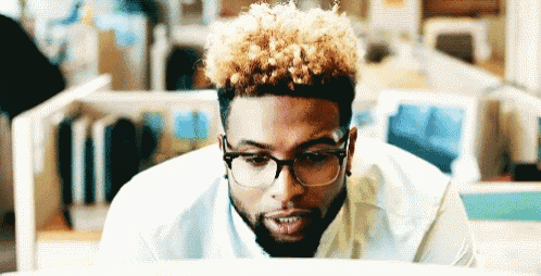 a man wearing glasses looks at a computer screen