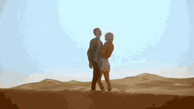 a man and a woman are dancing in a desert .
