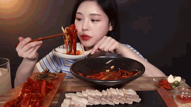 a woman is eating food with chopsticks and a bowl of food