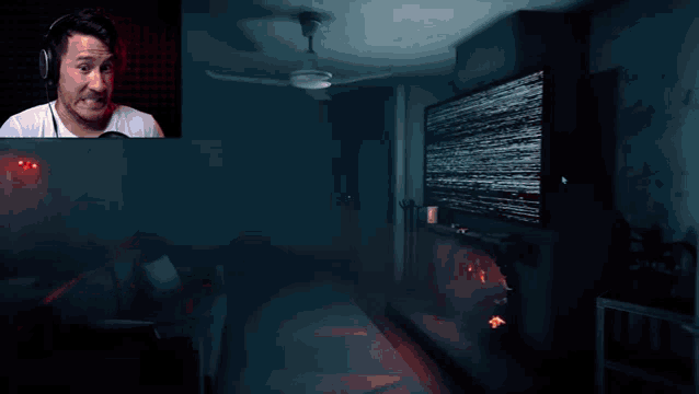 a man wearing headphones looks at a tv screen