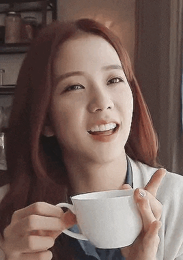 a woman is smiling while holding a cup of coffee .
