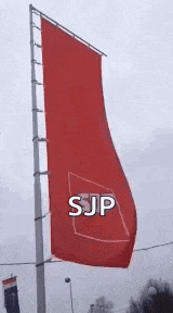a large red flag with the word sjp written on it is hanging from a pole .