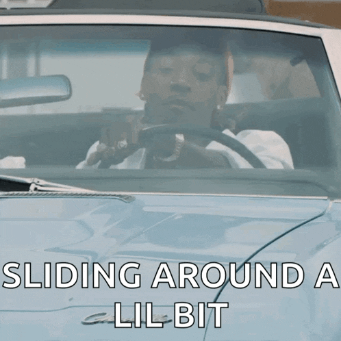 a man is driving a car with the words " sliding around a lil bit " on the hood