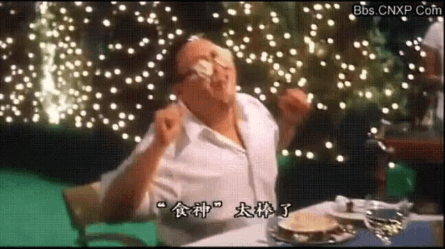 a man is sitting at a table with chinese writing on the screen