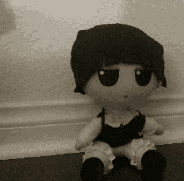 a black and white photo of a stuffed doll sitting on a floor