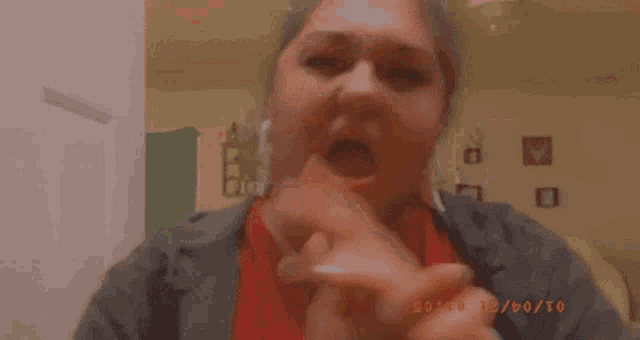 a woman is holding her hands up in front of her face and looking at the camera .