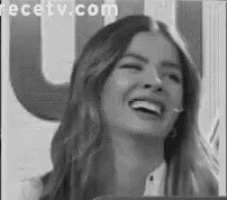 a black and white photo of a woman laughing with a microphone in her mouth .