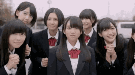 a group of young girls in school uniforms are standing next to each other .