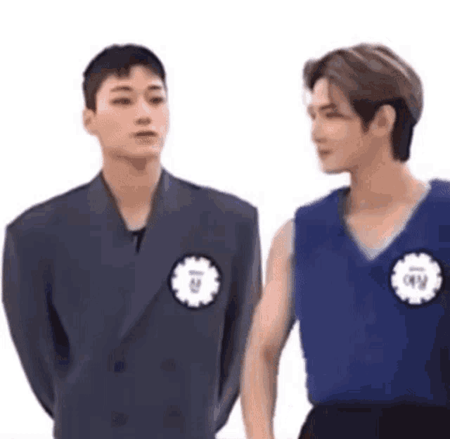 two men in suits and vests are standing next to each other and looking at each other .