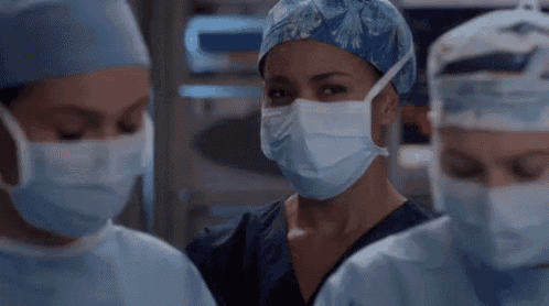 a group of female surgeons wearing surgical masks and scrubs .