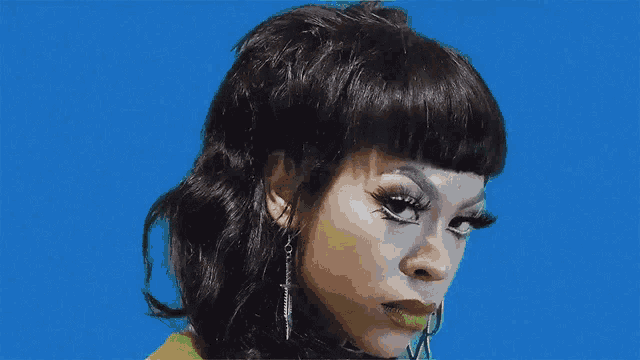 a woman with a mullet hairstyle and green lipstick is looking at the camera .