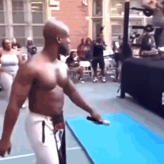 a shirtless man is standing on a blue mat in front of a crowd