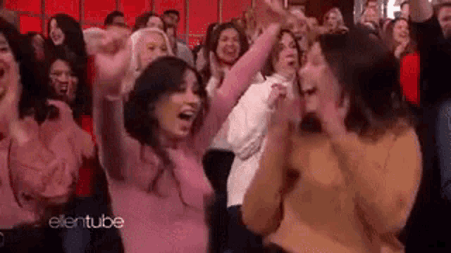 a crowd of people are sitting in a theatre with their arms in the air and laughing .