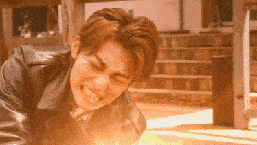 a man in a leather jacket is laying on the ground with his eyes closed