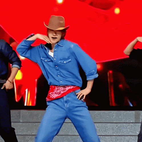 a man wearing a cowboy hat is dancing on stage