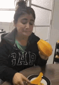 a woman wearing a gap sweatshirt is cutting a piece of fruit