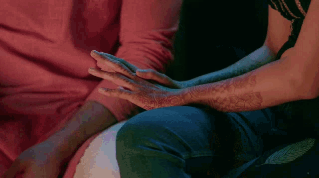 a man and a woman holding hands with henna on their arms