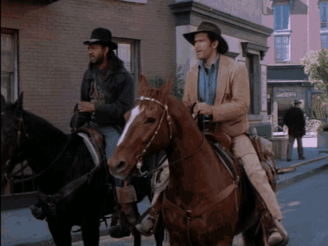 two men are riding horses down a street in front of a building that says ' abercrombie '