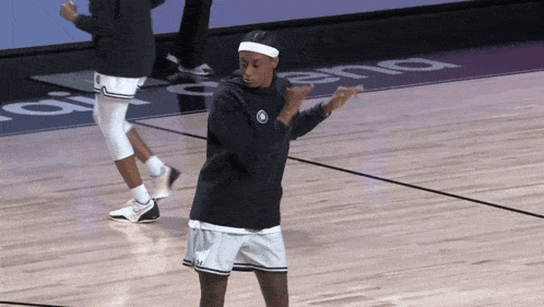 a man in a black shirt and white shorts stands on a basketball court