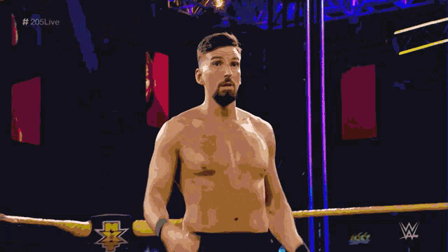 a shirtless wrestler in a wrestling ring with a hand reaching out towards him